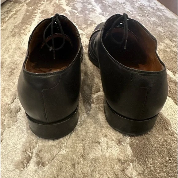 Gucci men’s black dress shoe with gold chain hardware.